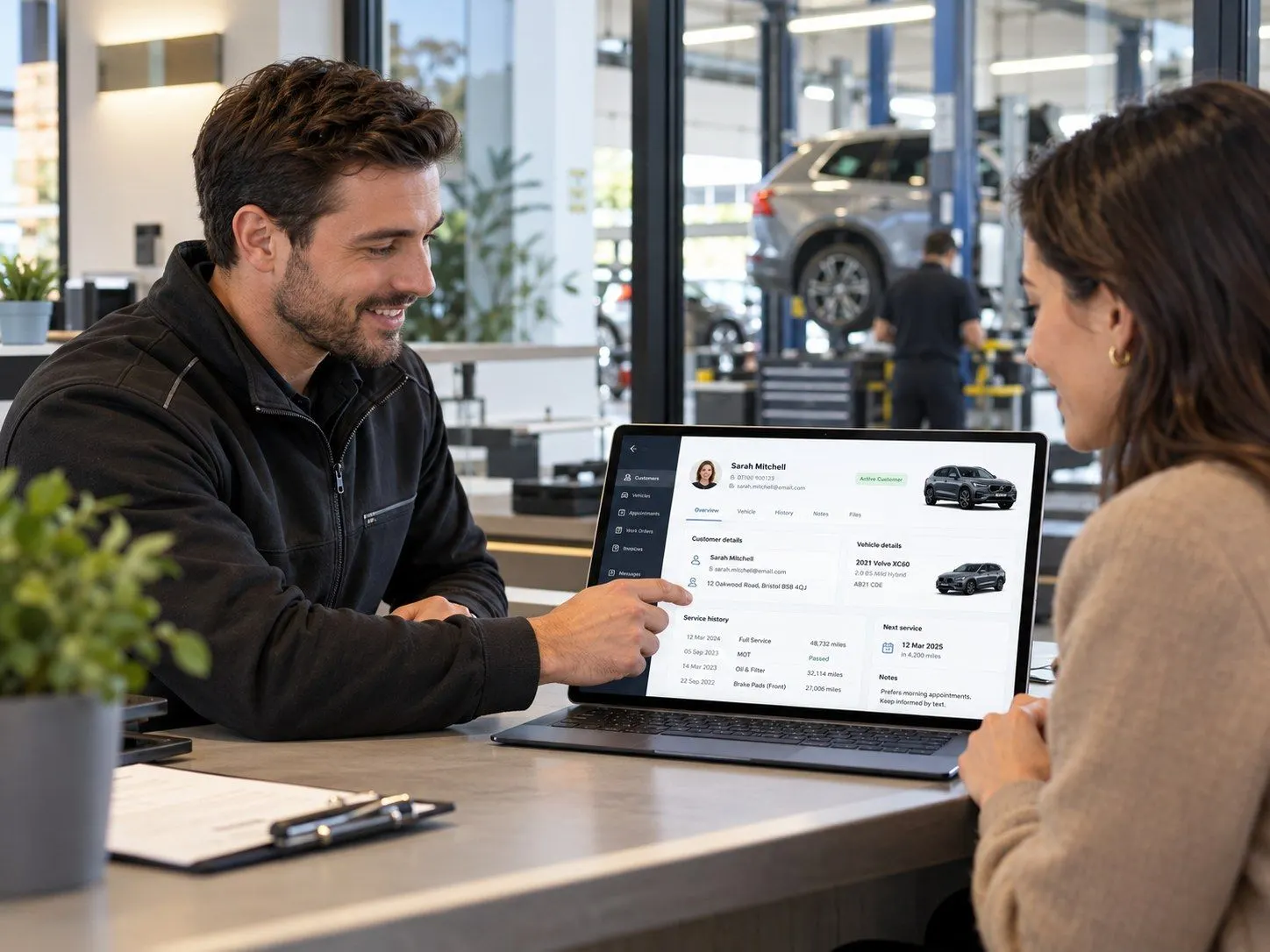 Service advisor showing a customer her vehicle record on a laptop